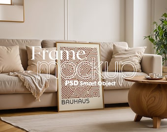 May include: A beige sofa with pillows and a throw blanket, a wooden coffee table with a cup and saucer, and a framed print with a geometric pattern and the word "BAUHAUS" in brown text.