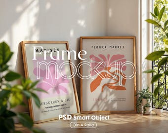 May include: Two framed art prints with wooden frames. The print on the left features a pink flower with the text "MATISSE" and "ERGGRUEN & CIE". The print on the right features an orange flower with the text "FLOWER MARKET" and "TOKYO".