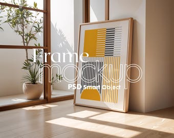 Könnte beinhalten: Ein gerahmter Kunstdruck mit einem geometrischen Design in Gelb, Schwarz und Weiß lehnt an einer Wand. Das Kunstwerk zeigt Halbkreise und rechteckige Formen. Der Text "Frame mockup PSD Smart Object" ist sichtbar.