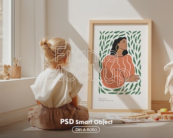 Può includere: Una stampa artistica incorniciata con una donna con una maglia arancione e orecchini d'oro, su uno sfondo di foglie verdi. La cornice è in legno chiaro. Il testo "Botanical Drawing Collection" è visibile. Un bambino è seduto davanti all'opera.