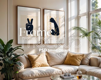 May include: Two framed prints on a wall above a beige couch with throw pillows. The print on the left features a black hand making a peace sign. The print on the right features a black arm flexing with the word "peace" repeated in black text.