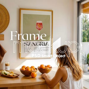 Puede incluir: Una imagen enmarcada en oro con una impresión de una copa de sangría. La imagen está colgada en una pared blanca sobre una mesa de madera con cuencos de naranjas y una vela.