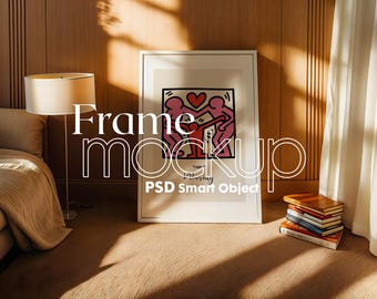 May include: A white frame mockup with a simple illustration of three people holding hands and a heart. The frame is on a wooden surface with a bed and a lamp in the background.