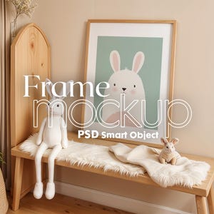Peut inclure: Une maquette de cadre en bois avec une illustration de lapin blanc à l'intérieur. Le cadre est posé sur un banc en bois avec un jeté en fausse fourrure blanche et un lapin en peluche blanc.