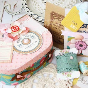 May include: A vintage-style craft box with a pink and white polka dot pattern, decorated with lace, flowers, and a sewing machine themed embellishment. The box has a label that says "Clase Knit 10 29 Fine Thread".
