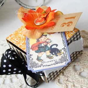 May include: A Halloween gift box with a black and white houndstooth pattern and a black polka dot bow. The box is decorated with an orange flower and a vintage Halloween card showing a child and a black cat. The tag reads "October 31".