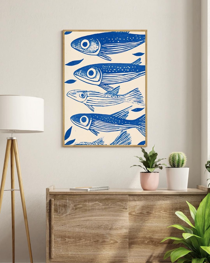May include: A framed print of a blue and white illustration of five fish swimming in a row. The fish are stylized and have a simple design. The background is a light cream color.