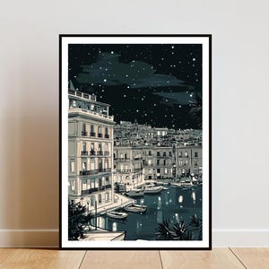 May include: Black framed art print depicting a nighttime cityscape with buildings, boats, and a starry sky. The illustration is in shades of gray and white, with lights illuminating the buildings and water. The artwork is displayed on a white wall.