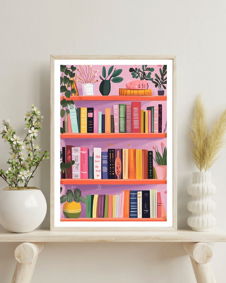 May include: A pink bookshelf with three shelves filled with books and plants. The shelves are made of wood and have a light pink background. There are various plants on the shelves, including a green plant with large leaves, a small potted plant with white flowers, and a green plant with small leaves. The books are all different colors and sizes, and some have titles visible.