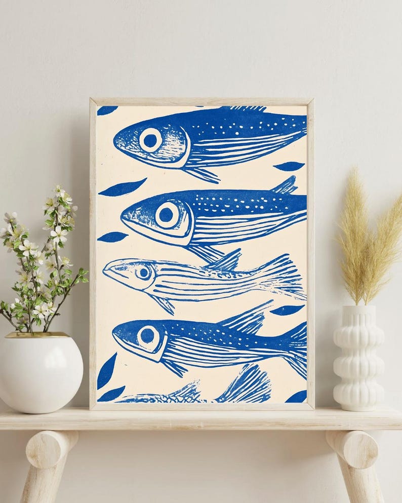 May include: A framed print of a blue and white illustration of four fish swimming in a row. The fish are stylized and have a simple design. The background is a light cream color.