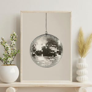May include: A framed print of a silver disco ball hanging from the ceiling against a beige background.