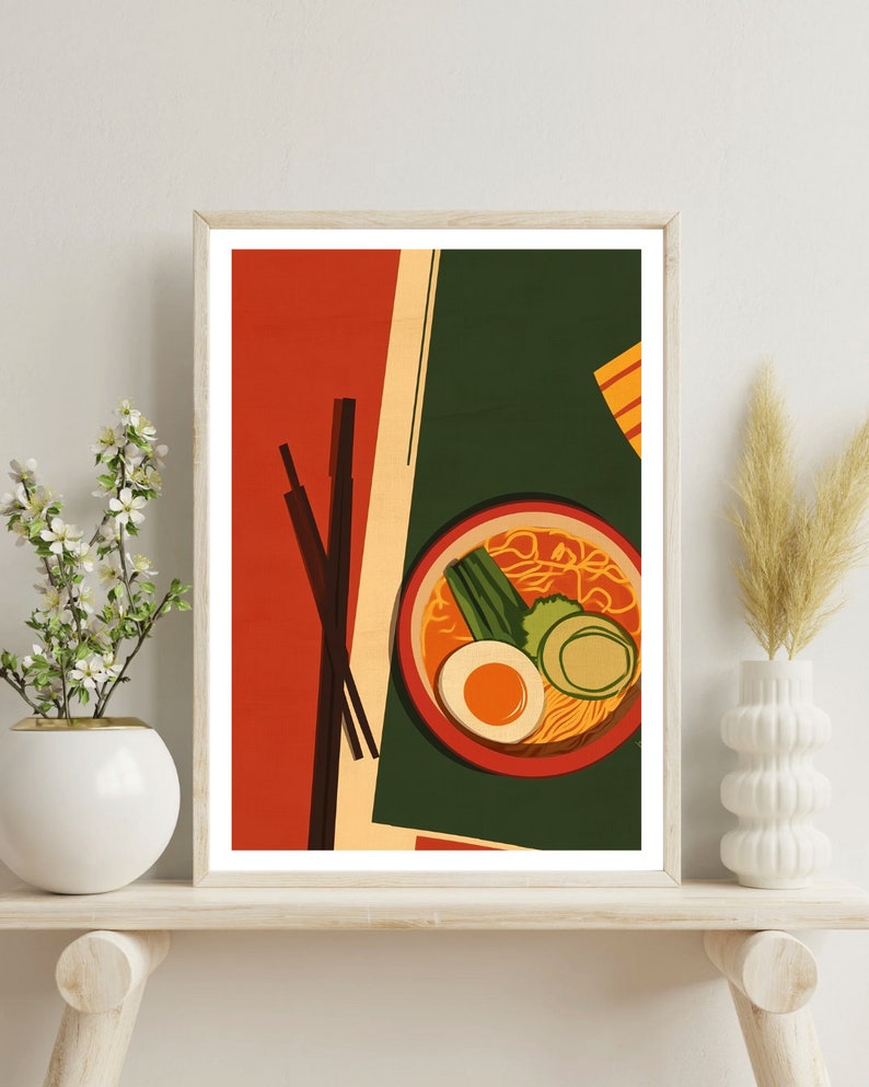 May include: A framed illustration of a bowl of ramen with chopsticks, egg, green onions, and a slice of cucumber. The background is a red and green colour scheme.