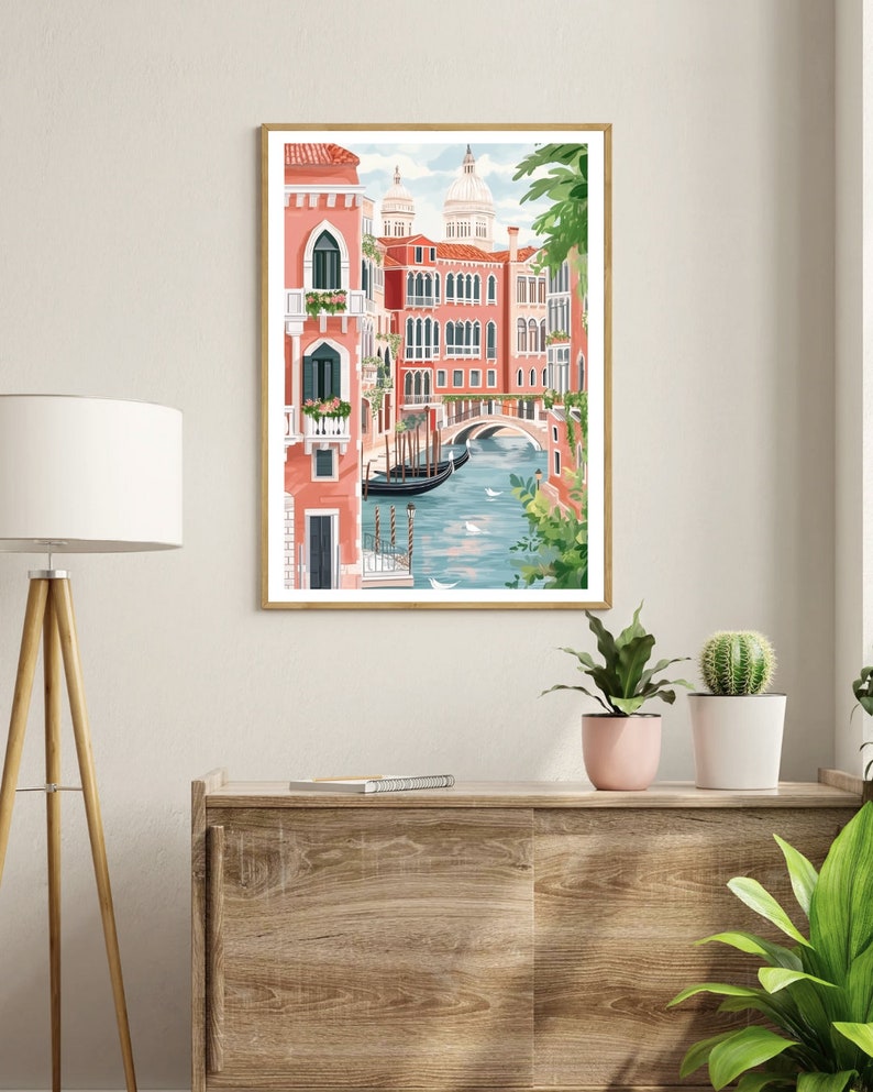 May include: A watercolor illustration of a canal in Venice, Italy. The canal is lined with pink buildings and a bridge. There are boats in the water and green trees in the foreground.