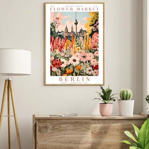 May include: A vintage-style poster advertising a flower market in Berlin, Germany. The poster features a colourful illustration of a flower garden with the Berlin TV Tower in the background. The text on the poster reads "Flower Market" and "Berlin".