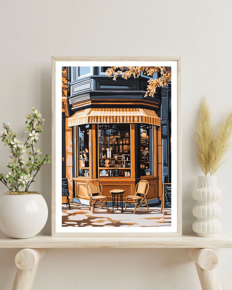 Op de afbeelding: Een winkelgevel met een gestreept luifel en grote ramen. Twee rieten stoelen en een kleine tafel staan ​​voor de winkel. De ramen zijn gevuld met planken vol producten, en de winkel is geschilderd in tinten blauw en geel.