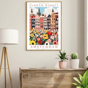 May include: A colorful poster with the text "Flower Market" and "Amsterdam" in red. The poster features a cityscape with colorful buildings and a field of flowers in the foreground.