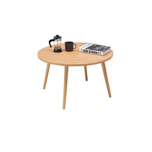 Pu&ograve; includere: Un tavolo rotondo in legno con quattro gambe. Una tazza da caff&egrave; nera e una french press di vetro sono sul tavolo, insieme a un libro intitolato "style at home".