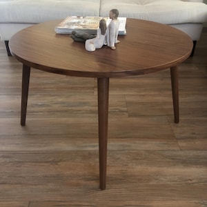 Pu&ograve; includere: Un tavolino da caff&egrave; rotondo in legno con quattro gambe. Il tavolo ha una finitura in legno naturale ed &egrave; decorato con due piccole figurine.
