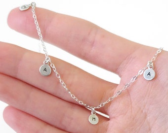 May include: Silver necklace with three charms, each with a letter engraved on it. The letters are A, M, and A.