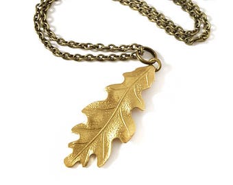 May include: A gold-toned necklace with a detailed oak leaf pendant. The chain is a delicate, linked style.