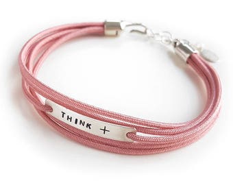 May include: A pink multi-strand bracelet with a silver charm that reads "THINK +"