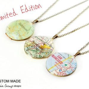 Puede incluir: Tres collares de cadena dorada con colgantes redondos con temática de mapas. Los colgantes presentan mapas de Baltimore, Filadelfia y San Francisco. Los collares están etiquetados como "Edición limitada".