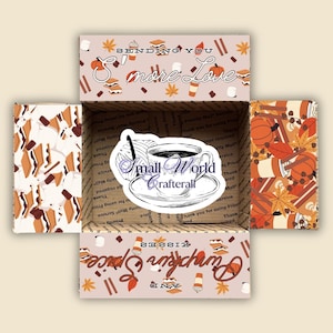 Könnte beinhalten: Ein offener Pappkarton mit herbstlichen Designs. Die Box zeigt Illustrationen von Kürbissen, Blättern und Kaffeetassen. Der Text "Sending You More Love" und "Pumpkin Spice Kisses" ist auf der Box zu sehen.