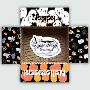 May include: An open cardboard box with Halloween-themed decorations. The box features a sticker with a coffee cup and the text "Small World Crafterall". The box is decorated with ghosts, pumpkins, and the word "Happy" and "Halloween".
