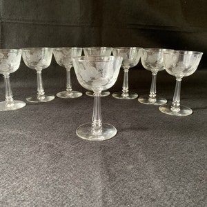 May include: Set of ten clear glass stemmed wine glasses with an etched floral design.
