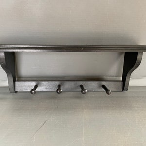 All-wood shelf with 4 pegs - painted black - with a groove for plate display