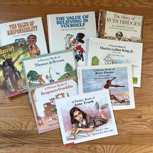 Op de afbeelding: Een verzameling van negen biografische prentenboeken voor kinderen met titels zoals The Value of Responsibility, The Value of Believing in Yourself, The Story of Ruby Bridges, Harriet Tubman, en prentenboeken over Thomas Jefferson, Benjamin Franklin, Martin Luther King, Jr., Jesse Owens en Anne Frank.