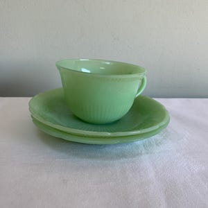May include: A set of vintage green teacup and saucer. The cup and saucer are made of jadeite glass and have a delicate floral pattern.