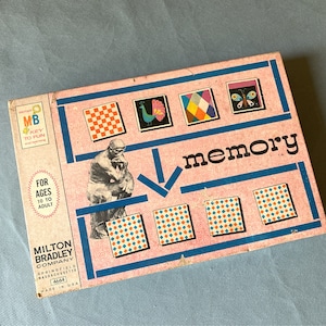May include: A vintage Milton Bradley Memory board game box with a pink background and blue accents. The box features an illustration of The Thinker statue, the word memory, and various square tiles displaying patterns like a peacock and butterfly.