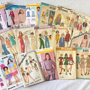 May include: A selection of vintage sewing patterns from brands including Simplicity, Butterick, and McCall's. The patterns showcase illustrations of clothing designs, such as dresses, skirts, and jackets. The patterns are in various sizes and styles, with a retro aesthetic.