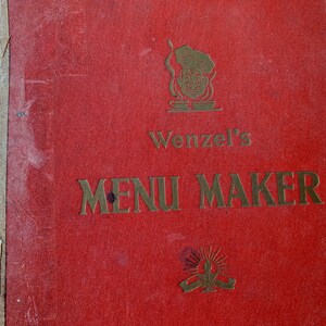 May include: Red book with gold lettering that reads "Wenzel's Menu Maker". A cartoon chef with a white hat and a smile is pictured above the title.