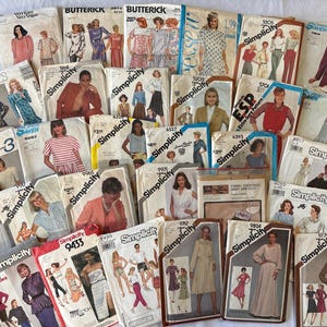 May include: A collection of vintage sewing patterns from brands like Simplicity, Butterick, and McCall's. The patterns feature illustrations of various clothing designs, including dresses, blouses, and skirts. The patterns are in various colors and sizes.