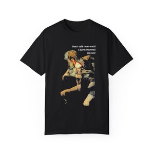 以下が含まれることがあります： 絵画がプリントされた黒いTシャツ。絵画には、苦悩した表情で小さな人形を手に持つ人物が描かれている。絵画の上には「息子を食い尽くすまで話しかけないで！」という文字がプリントされている。