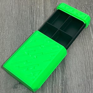 May include: Bright green rectangular storage box with a sliding lid. The box is divided into six compartments. The lid and the box have a textured design. The box is open, revealing the dark green interior.