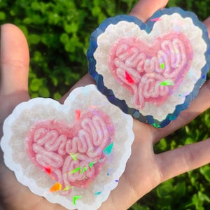 May include: A handmade wooden sign with the text "Welcome" in a playful font. The sign is painted white with a distressed finish, and features a decorative floral design in shades of pink and green. It is designed for indoor or outdoor use.