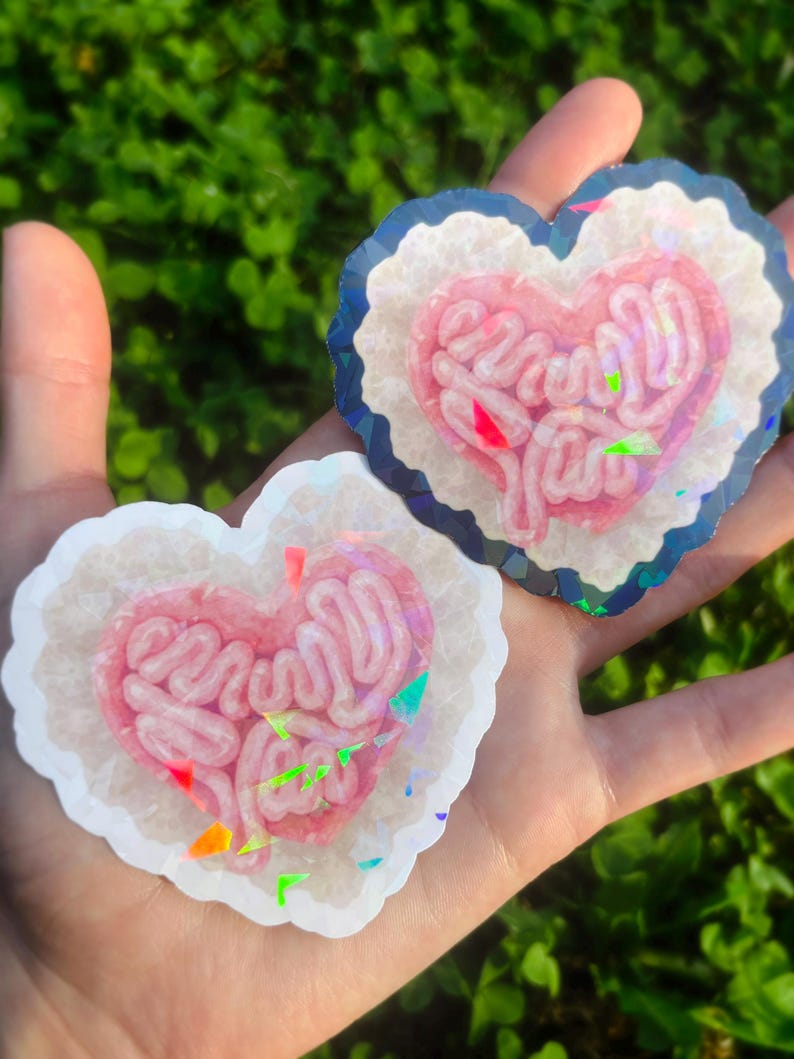 May include: A handmade wooden sign with the text "Welcome" in a playful font. The sign is painted white with a distressed finish, and features a decorative floral design in shades of pink and green. It is designed for indoor or outdoor use.