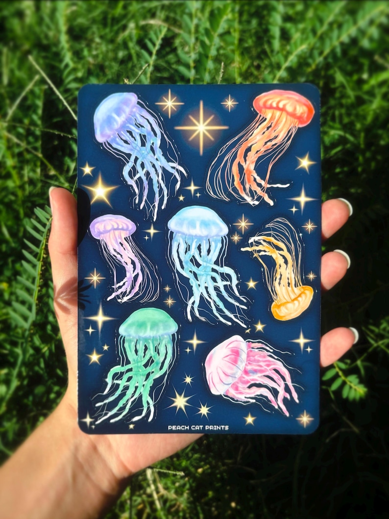Pu&ograve; includere: Una stampa rettangolare blu scuro con illustrazioni di meduse colorate. Le meduse sono in tonalit&agrave; di rosa, arancione, giallo, verde e blu, con accenti di stelle. Il testo "PEACH CAT PRINTS" &egrave; in basso.