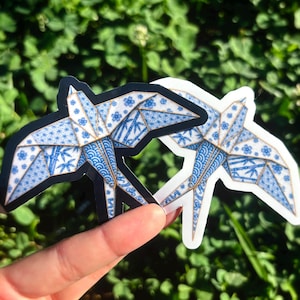 May include: Two swallow-shaped stickers featuring a blue and white pattern reminiscent of traditional porcelain, with intricate floral and bamboo motifs. One sticker has a black border, while the other has a white border, both depicting a bird in flight.