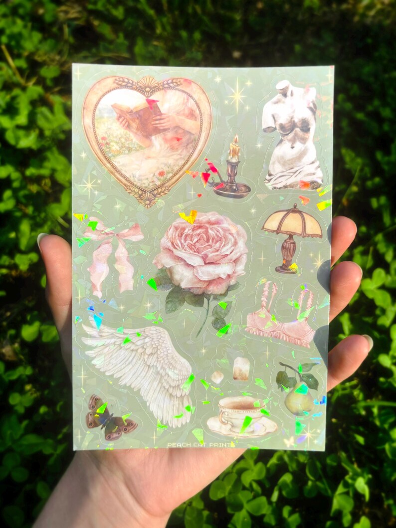 Puede incluir: Una hoja de pegatinas con fondo verde claro y varios dise&ntilde;os. Las pegatinas incluyen un marco en forma de coraz&oacute;n con una pintura, un busto, una rosa, una l&aacute;mpara, una taza de t&eacute;, una mariposa y un ala. El texto "PEACH CAT PRINTS" est&aacute; en la parte inferior.
