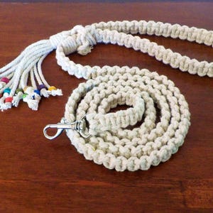 Può includere: Un guinzaglio per cani in corda di cotone bianco con un fiocco di perline colorate e un moschettone argentato.