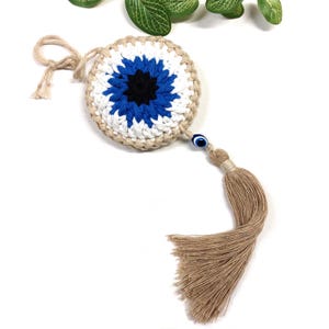 May include: Crocheted blue and white evil eye charm with a beige tassel and a blue evil eye bead.