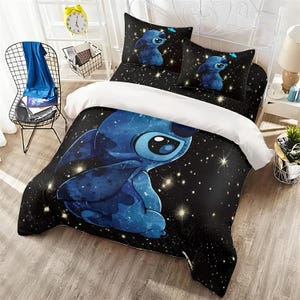 May include: A blue and black comforter set featuring a cartoon character design. The bedding set includes a comforter and two pillowcases. The comforter has a black background with a starry design and a large blue cartoon character.