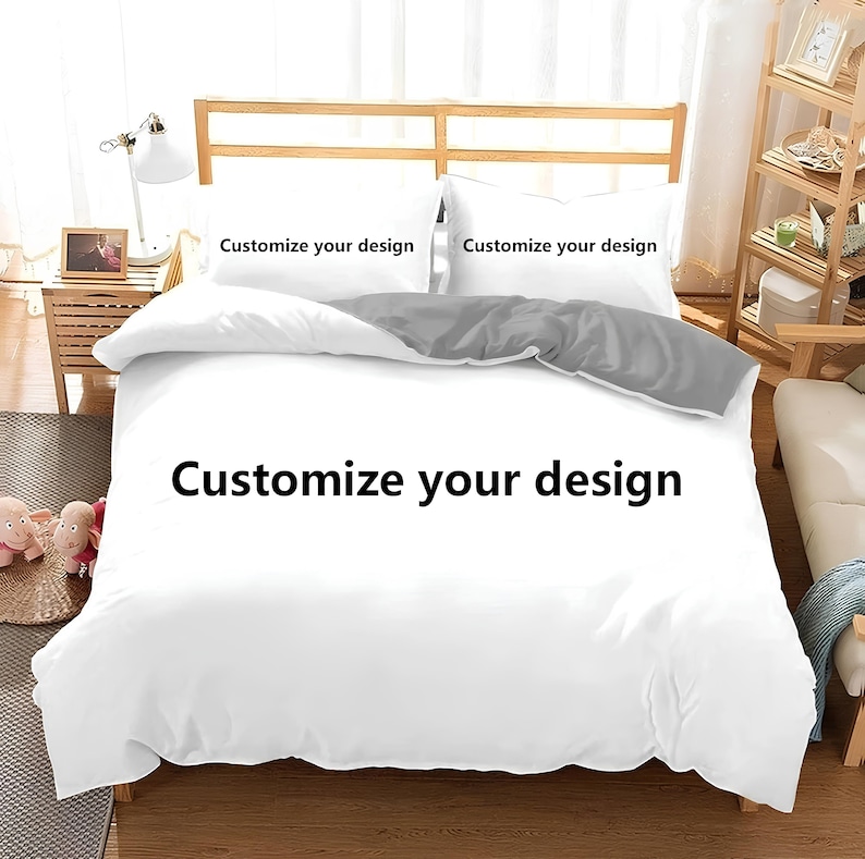 Puede incluir: Funda n&oacute;rdica blanca con una almohada gris de acento. La funda n&oacute;rdica tiene el texto "Personaliza tu dise&ntilde;o" impreso en ella.