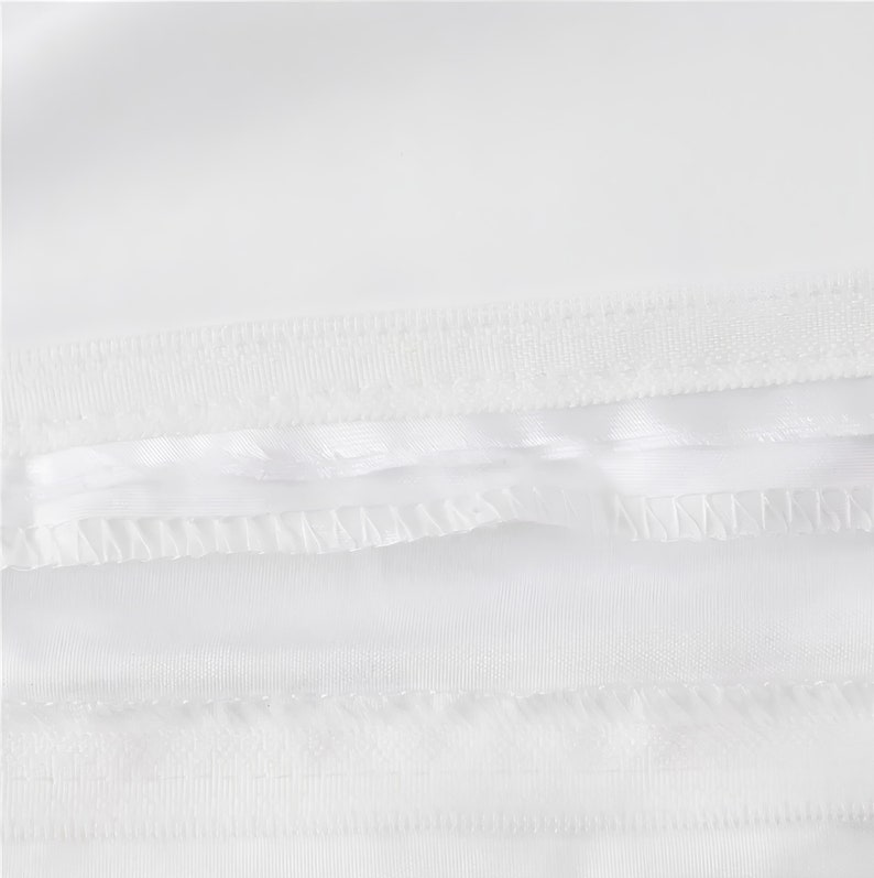 Puede incluir: Primer plano de una tela blanca con una doble fila de costuras a lo largo del borde inferior.