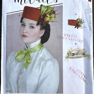 May include: McCall's sewing pattern featuring a woman wearing a rust-colored hat with a green bow and floral accents. The pattern includes illustrations and the text "Angela Clayton". The pattern is marked "Excess Discontinued".