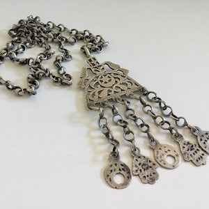 Può includere: Una collana d'argento con un grande ciondolo decorato con un motivo geometrico e cinque ciondoli più piccoli pendenti. Il ciondolo è finemente dettagliato con tagli e lavori a filigrana.